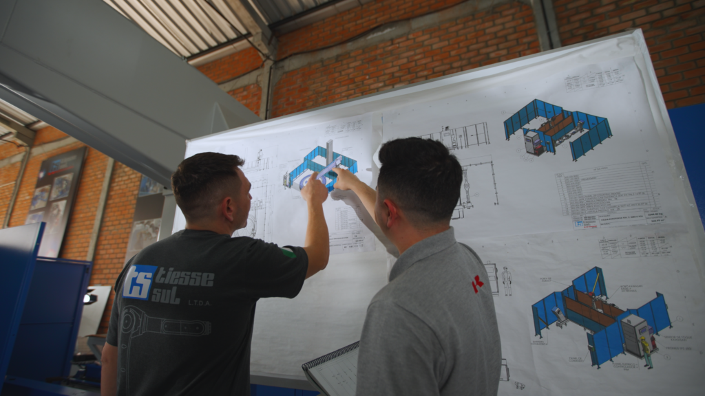 Dois técnicos da Tiesse Sul Robótica analisando o projeto de um robô industrial